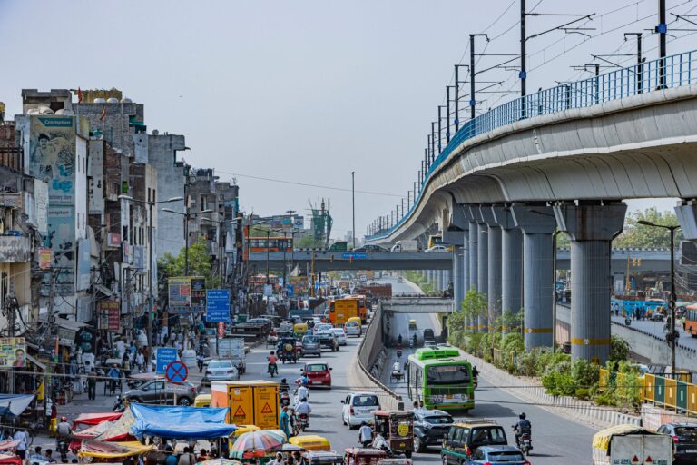 bustling street with elevated metro in delhi