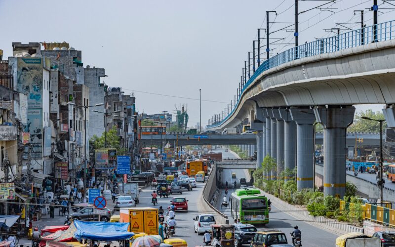 bustling street with elevated metro in delhi